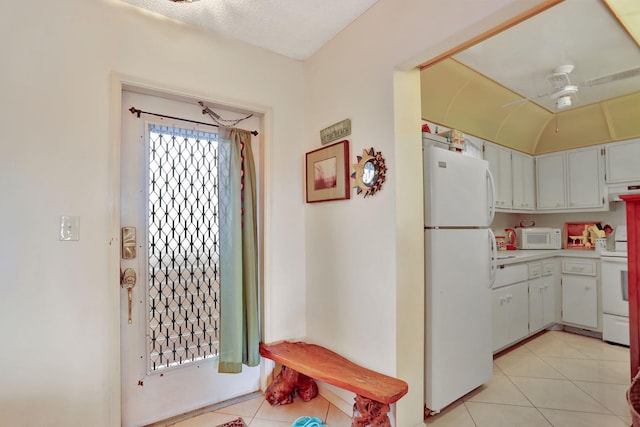 kitchen featuring white appliances, light tile patterned floors, ceiling fan, and white cabinets