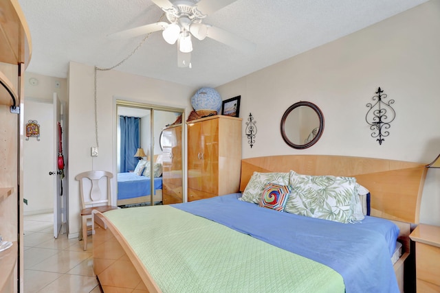 bedroom featuring light tile patterned floors, ceiling fan, a textured ceiling, and a closet