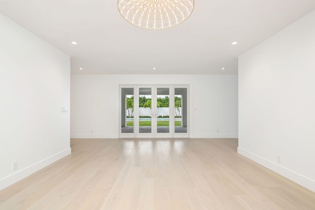 empty room featuring french doors and light hardwood / wood-style flooring