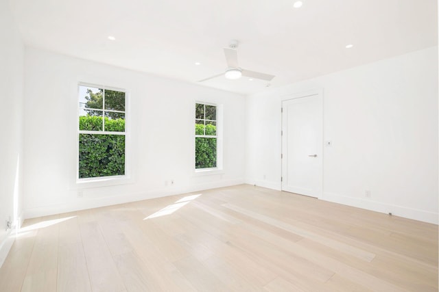 spare room featuring light wood-type flooring, ceiling fan, and a healthy amount of sunlight