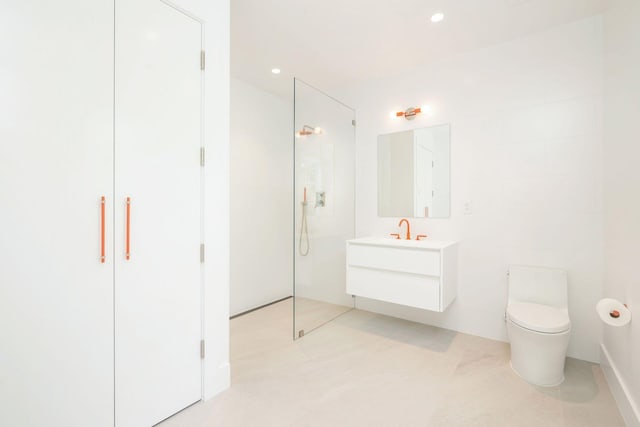 bathroom with walk in shower, vanity, and toilet