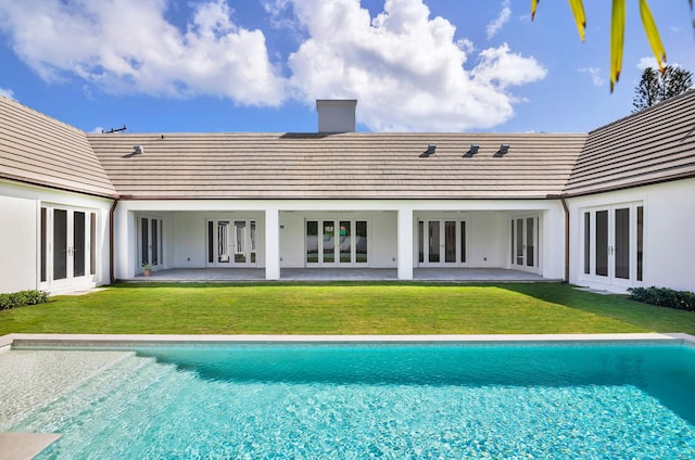 rear view of property featuring a patio, a yard, and french doors