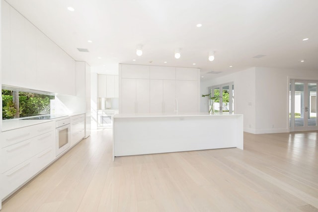 kitchen featuring light wood-type flooring, oven, a center island, and white cabinets