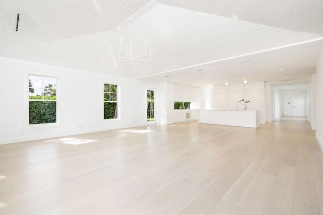 unfurnished living room featuring light hardwood / wood-style floors, an inviting chandelier, and high vaulted ceiling