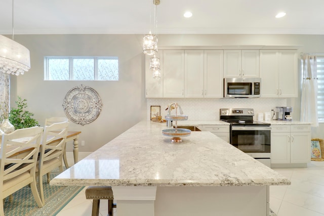 kitchen featuring hanging light fixtures, white cabinets, sink, and appliances with stainless steel finishes