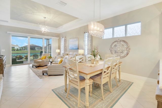 dining area featuring light tile patterned floors, an inviting chandelier, and a tray ceiling