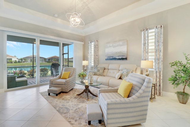 tiled living room with a wealth of natural light, a raised ceiling, a water view, and a notable chandelier