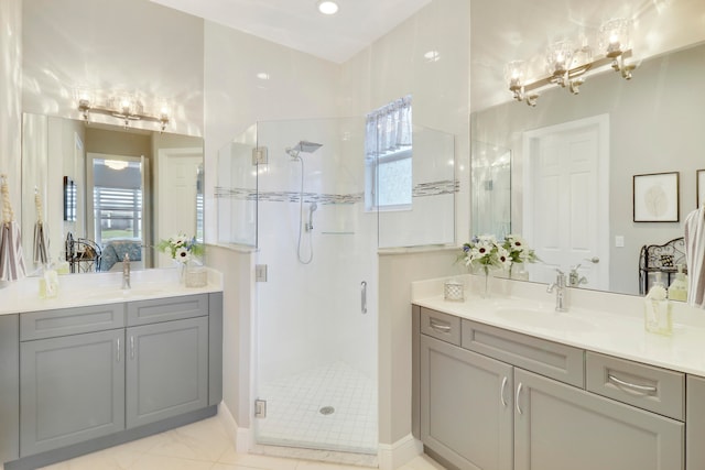 bathroom with vanity, a shower with shower door, a healthy amount of sunlight, and tile patterned floors