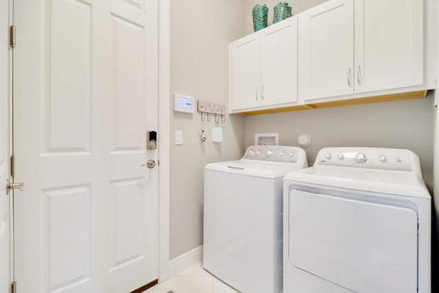 laundry area featuring cabinets, light tile patterned floors, and separate washer and dryer