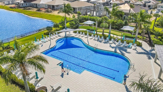 view of pool featuring a lawn, a water view, and a patio area