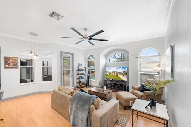 living room with ceiling fan, ornamental molding, and light wood-type flooring