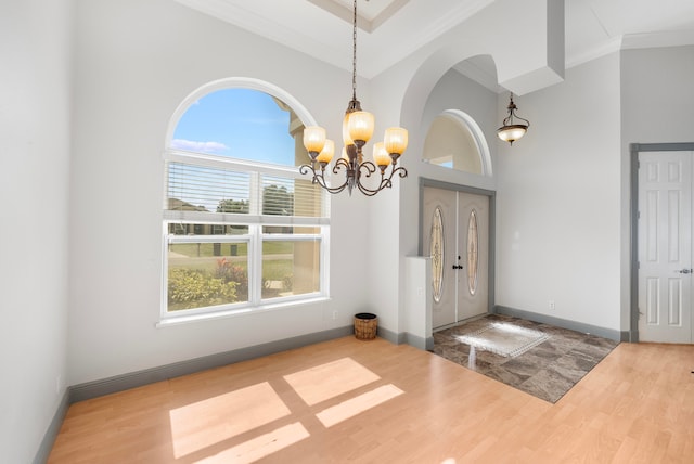 interior space featuring hardwood / wood-style floors, a notable chandelier, crown molding, and a towering ceiling