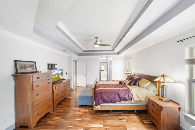 bedroom with crown molding, a raised ceiling, and hardwood / wood-style floors