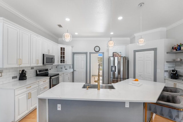 kitchen with a center island with sink, pendant lighting, light stone countertops, and stainless steel appliances