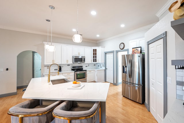 kitchen featuring light wood-type flooring, stainless steel appliances, sink, and pendant lighting