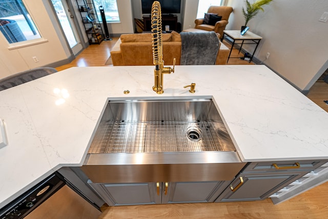 interior details with gray cabinets, light stone countertops, and light hardwood / wood-style flooring