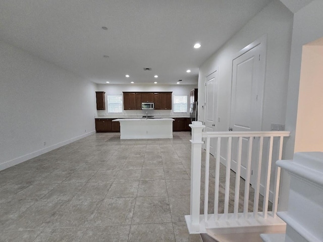 kitchen with stainless steel appliances, recessed lighting, light countertops, a kitchen island, and dark brown cabinetry