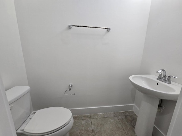 half bath with tile patterned flooring, baseboards, and toilet