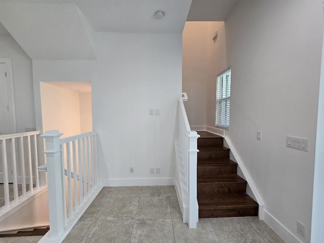 staircase featuring baseboards and tile patterned floors