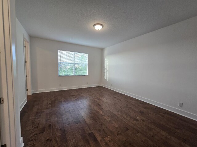 spare room with dark wood-style floors, baseboards, and a textured ceiling