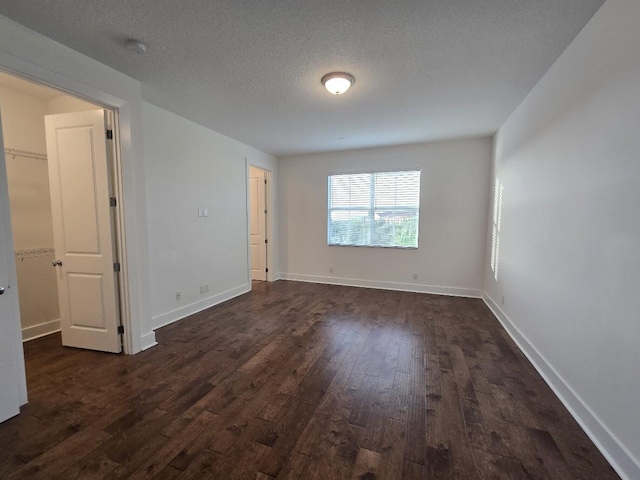 unfurnished room with dark wood-style floors, a textured ceiling, and baseboards