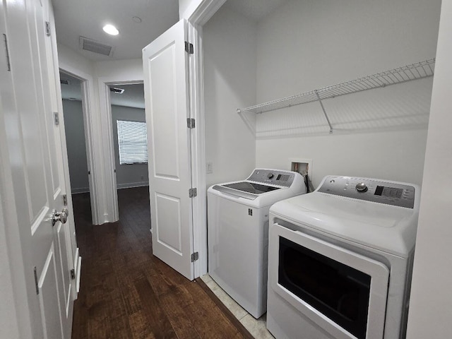 laundry area with laundry area, wood finished floors, washing machine and dryer, and visible vents