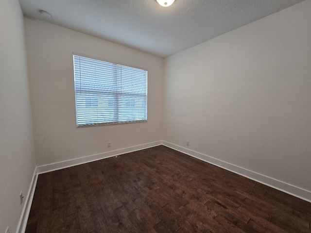 spare room with dark wood-style floors and baseboards