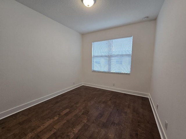 empty room featuring dark wood-style floors and baseboards