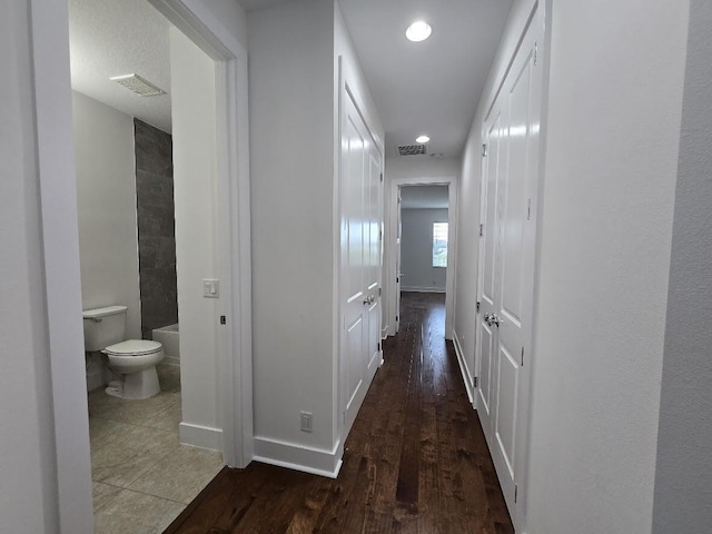 hall with recessed lighting, wood finished floors, visible vents, and baseboards