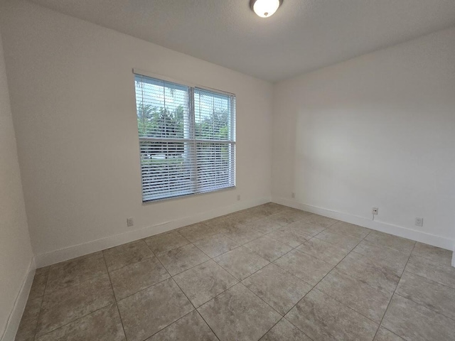 unfurnished room featuring light tile patterned floors and baseboards