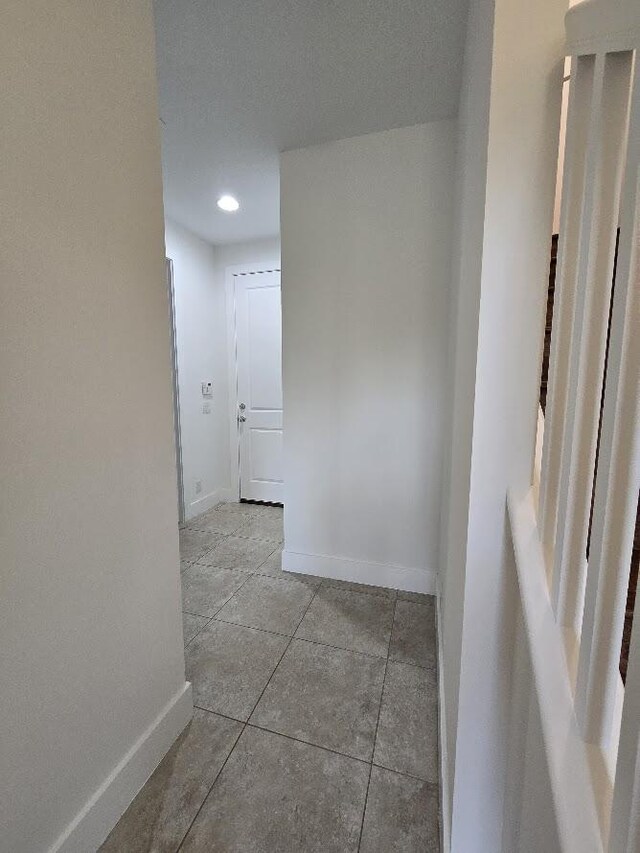 hall featuring light tile patterned floors and baseboards