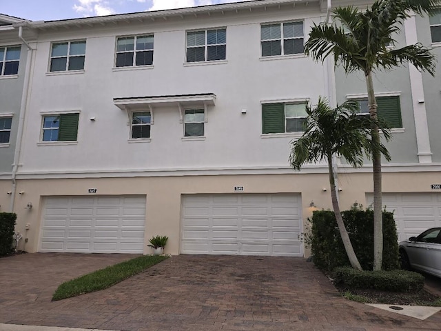 view of front of home featuring driveway, an attached garage, and stucco siding