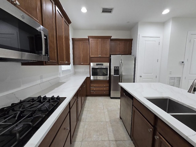 kitchen with light stone counters, stainless steel appliances, recessed lighting, visible vents, and a sink