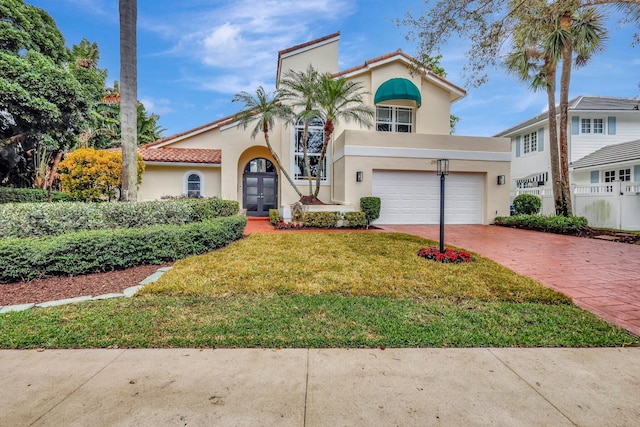 mediterranean / spanish home featuring a garage and a front yard