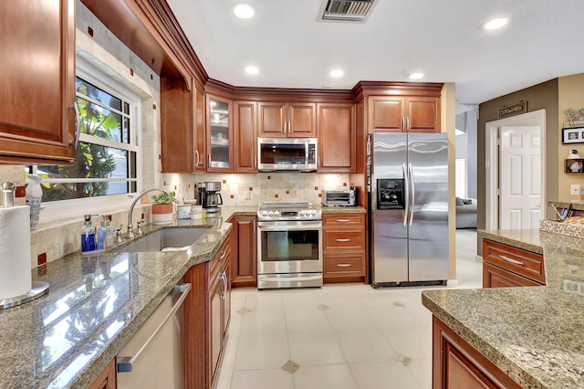 kitchen featuring backsplash, light stone counters, sink, and stainless steel appliances