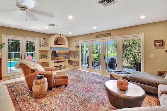 living room with french doors, built in features, ceiling fan, and light tile patterned flooring