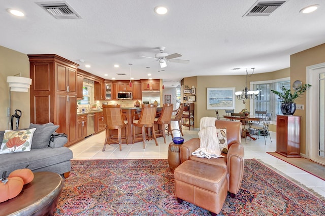 tiled living room with a textured ceiling, a wealth of natural light, and ceiling fan with notable chandelier