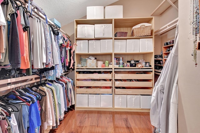 spacious closet with light hardwood / wood-style floors and vaulted ceiling