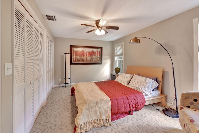 bedroom with ceiling fan, light carpet, and a closet