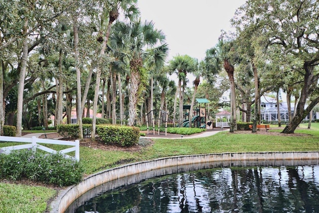 surrounding community featuring a lawn, a playground, and a water view