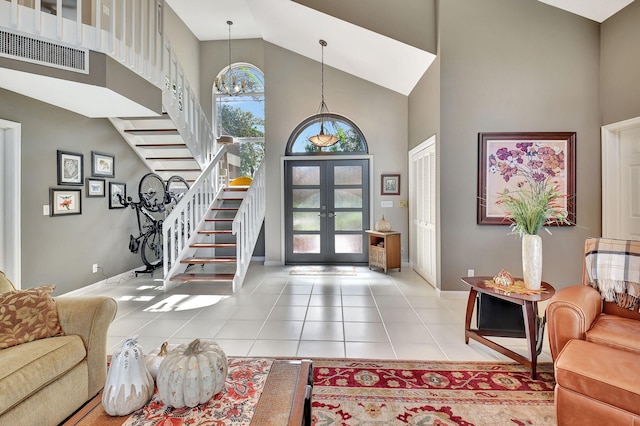 tiled foyer with a chandelier, high vaulted ceiling, and french doors