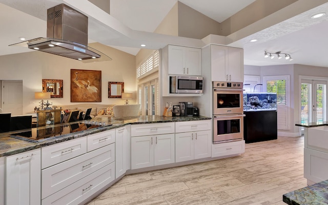 kitchen featuring island range hood, stainless steel appliances, vaulted ceiling, white cabinets, and light hardwood / wood-style floors