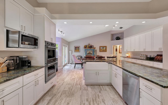 kitchen with lofted ceiling, white cabinets, kitchen peninsula, and stainless steel appliances