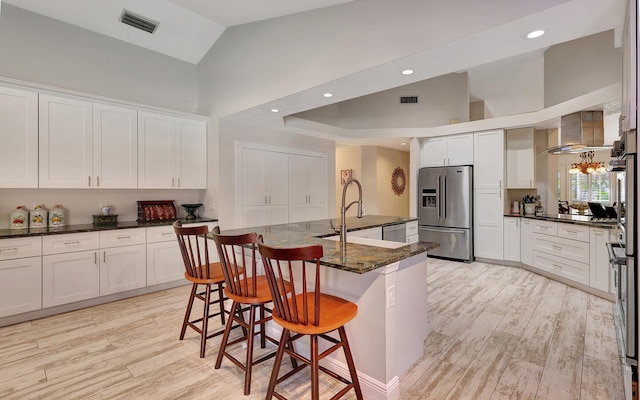 kitchen with a kitchen island with sink, a kitchen breakfast bar, light hardwood / wood-style flooring, white cabinetry, and appliances with stainless steel finishes