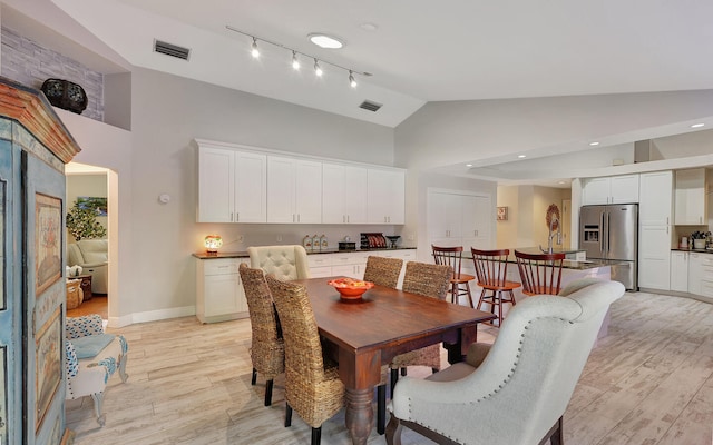 dining area with high vaulted ceiling and light wood-type flooring