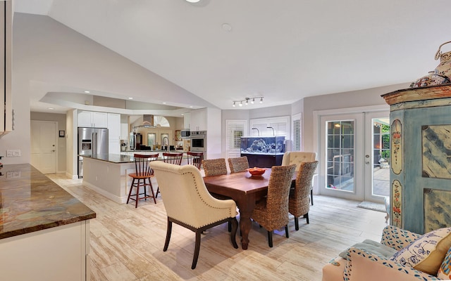 dining space with lofted ceiling, french doors, and light hardwood / wood-style flooring