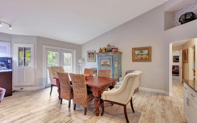 dining area featuring light hardwood / wood-style flooring and high vaulted ceiling