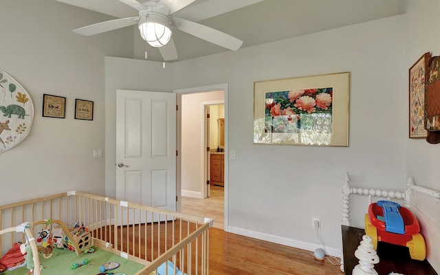 bedroom featuring light hardwood / wood-style flooring, ceiling fan, and a nursery area