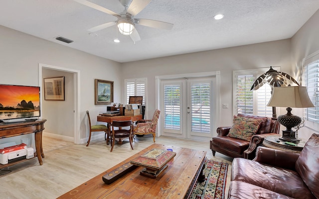 living room featuring french doors, light hardwood / wood-style flooring, a textured ceiling, and ceiling fan