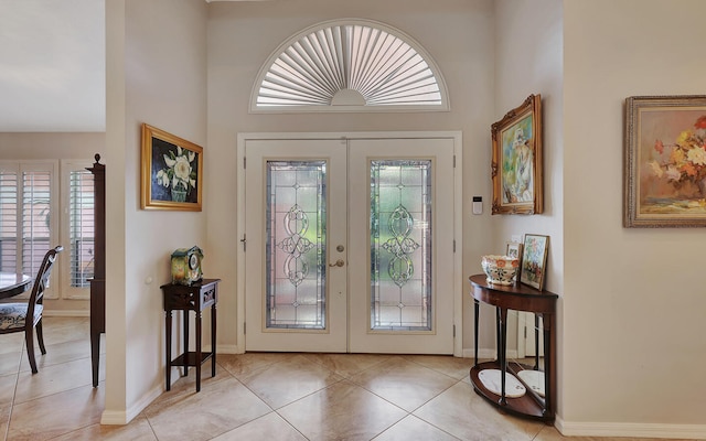 tiled entrance foyer with a towering ceiling, french doors, and a wealth of natural light